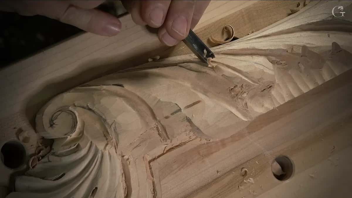 A curl of shaving lifts off the ridge of a scroll as the knife travels along the pencil line