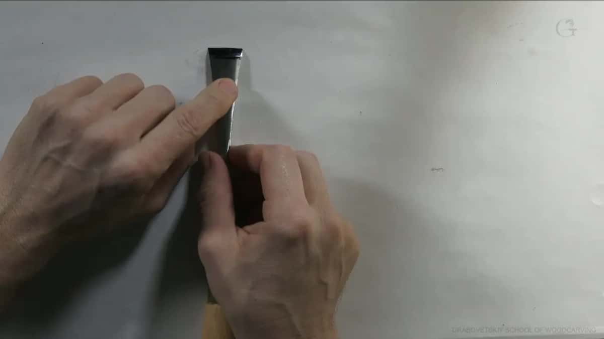 Held up against a plain background, a single carving gouge shows its beveled tip clearly.