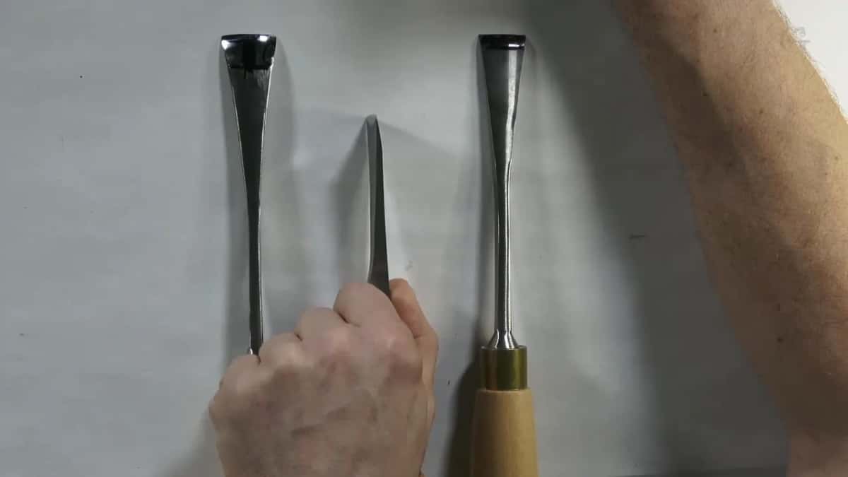 Two gouge blades held up side by side against a white ground with a small blade between them, sweeps toward the camera