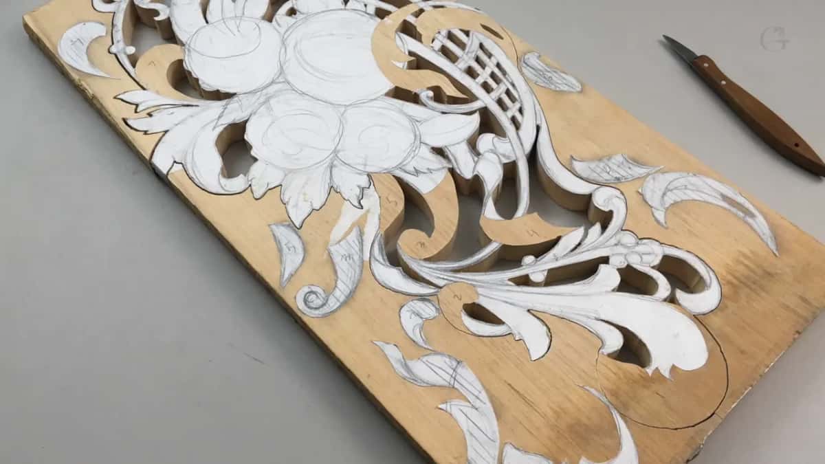 A narrow pale board carrying a whole paper pattern of flowers and scrolls, with depth numbers penciled between the shapes.