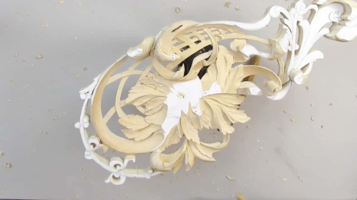 Lace-like openwork lies on a grey benchtop, half of it painted white and half bare wood.