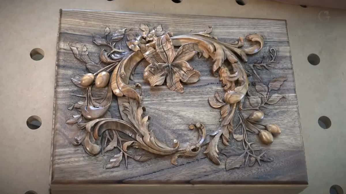 Leaves and one open flower stand polished above a dark figured board.