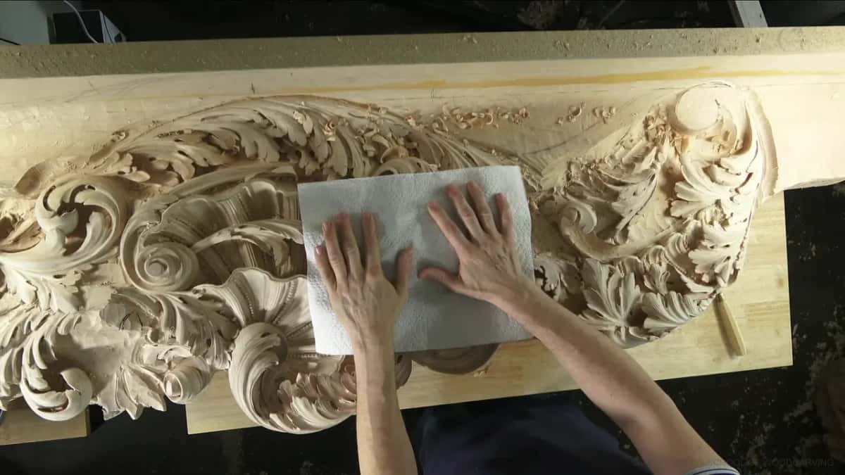 A folded paper towel is pressed flat over the middle of the frieze by both hands.
