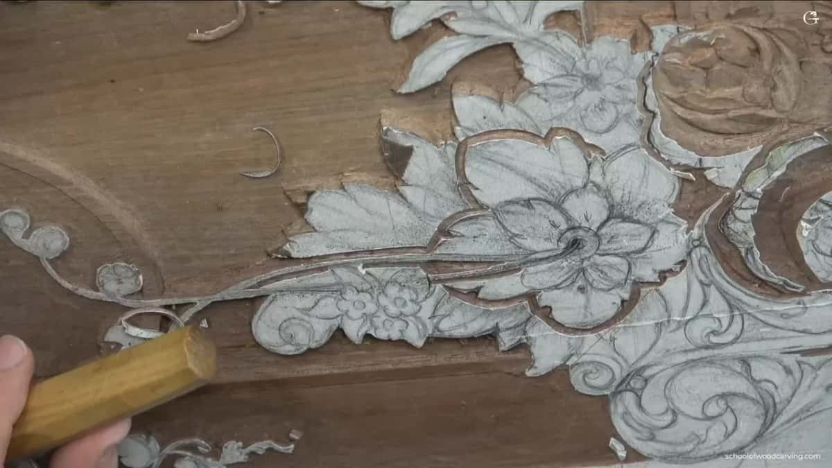 Grey paper drawing glued to a wide panel, its flower outlines already carved down to bare wood.