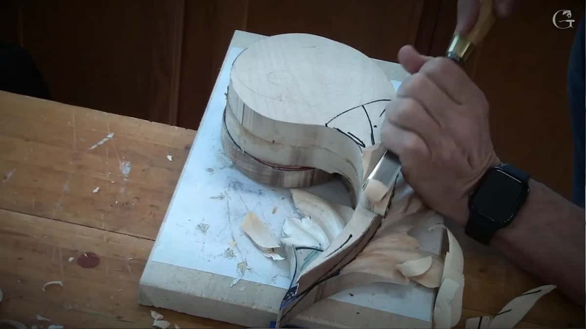Wood shavings and saw marks cover the bench around this large roughed-out spiral, a gouge still shaping its face.