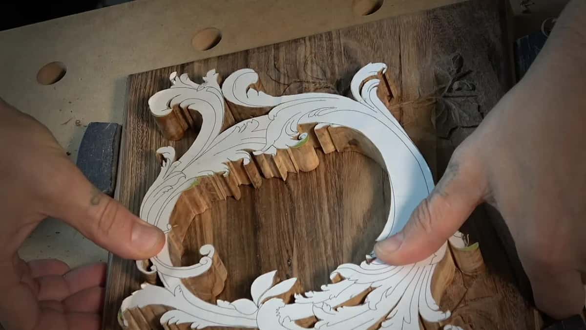 Printed scroll pattern laid over a partly carved wood block for layout.