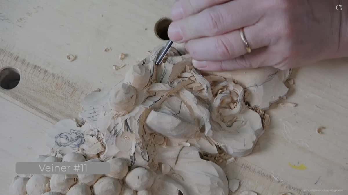 Veiner gouge shaping fine detail into a carved rose and leaf design.