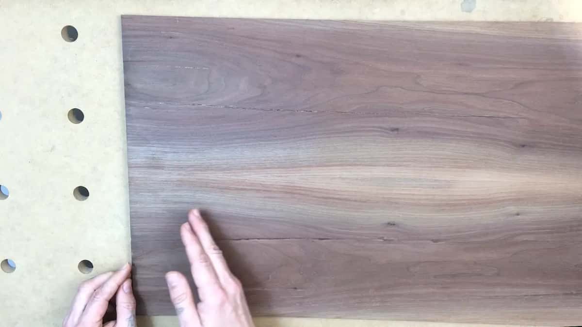 Close view of a wide dark brown board, straight grain running long, with a paler tan band low across it.
