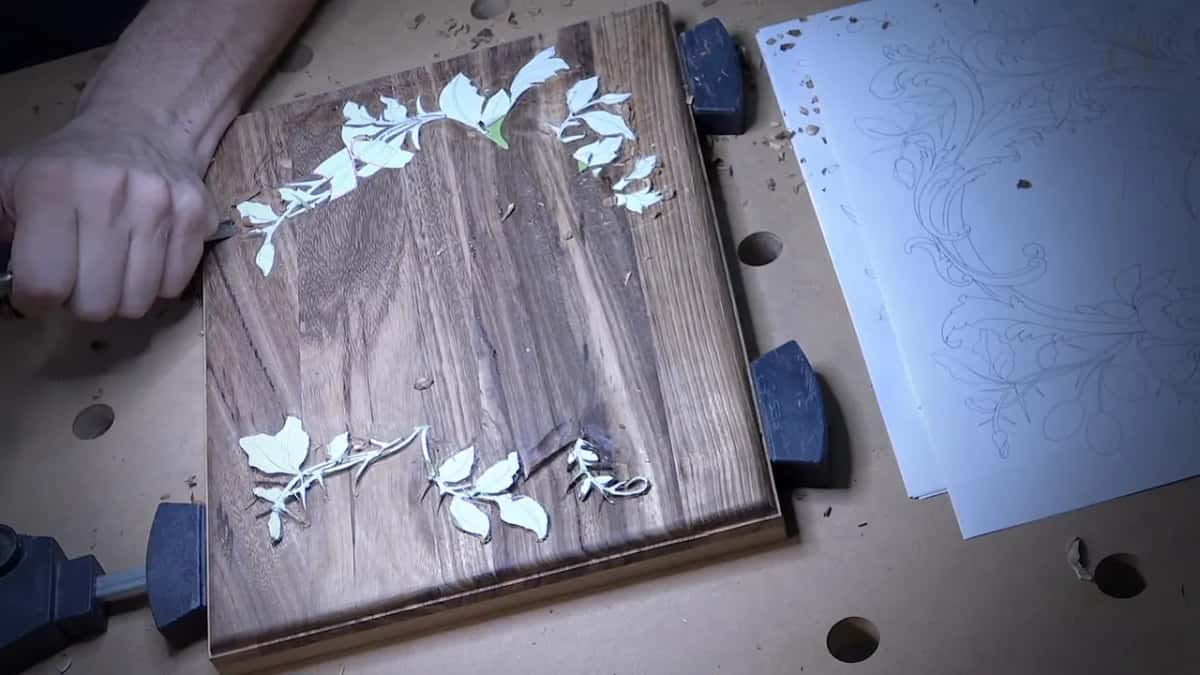 Seen from above, a dark clamped board carries a pale leaf border, with the pencil drawings beside it.