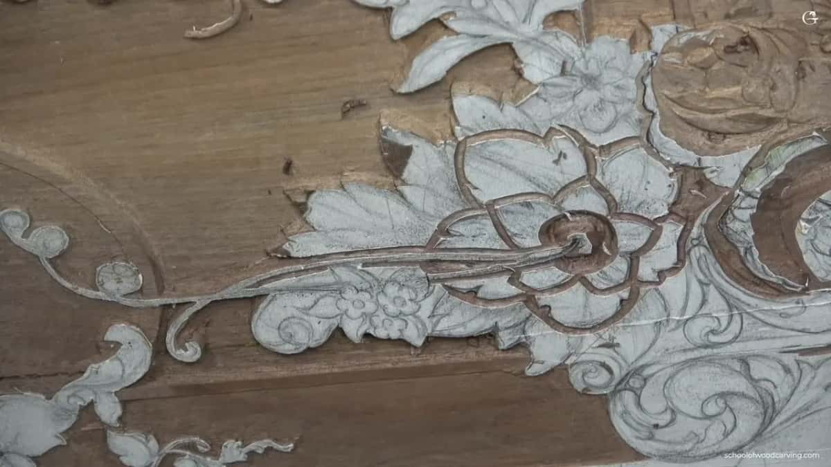 The design shows up white against a brown board, with the ground already carved away around the flowers.