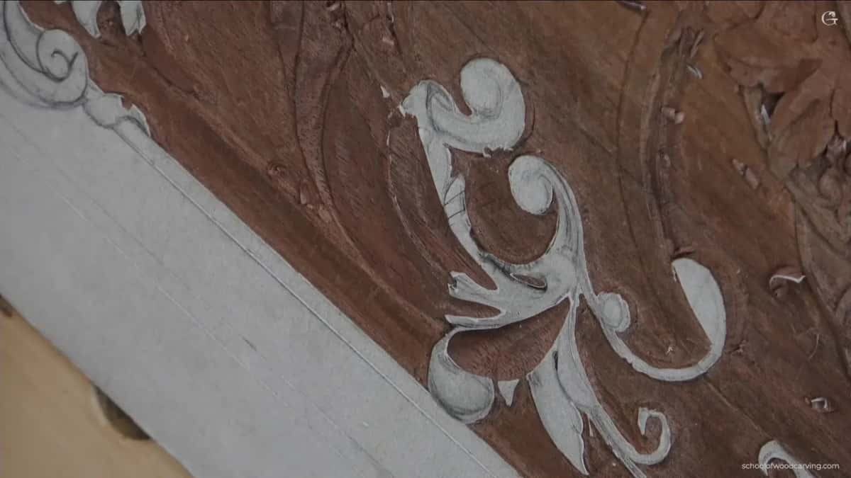Set against deep red brown wood, a pale scroll stands out with its carved edges catching the light.