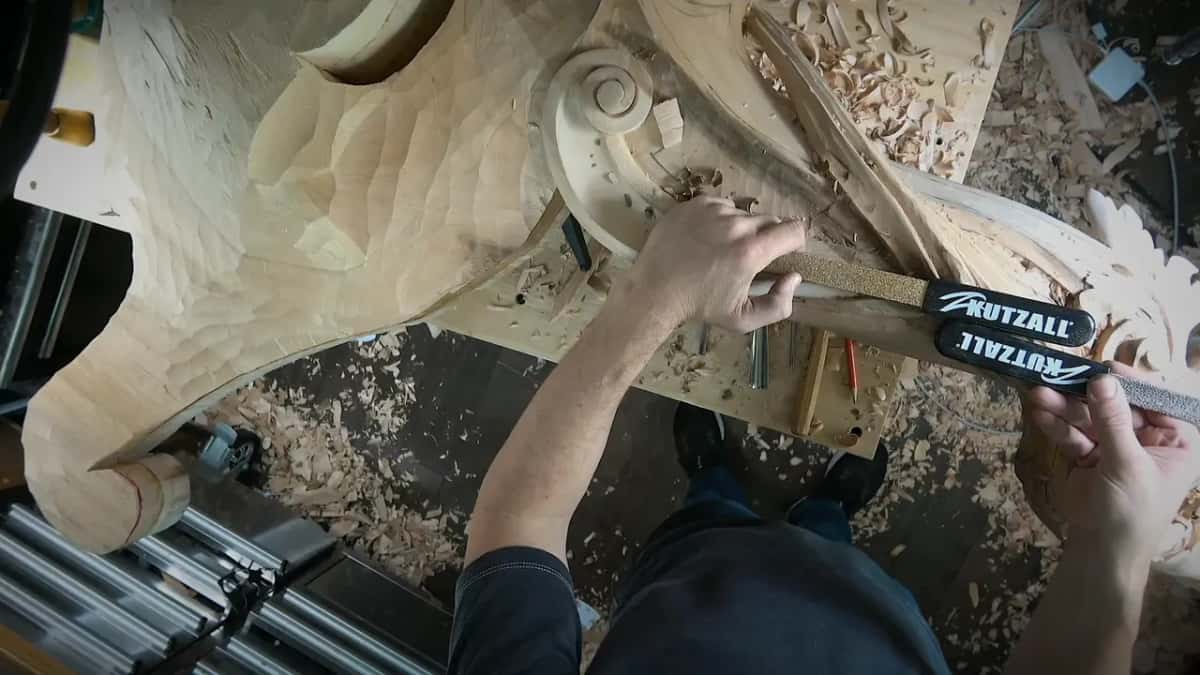 Two rasps with Kutzall labels held over the carving, the scroll just behind them