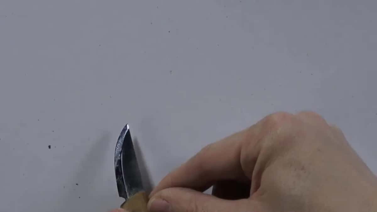 Factory bevel on a knife blade, held up to the camera over a white surface