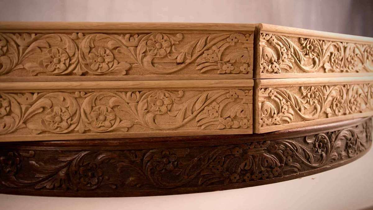 Alt text: Close-up of beautifully carved wooden drawer fronts featuring floral designs. The piece showcases detailed wood carving techniques, perfect for those interested in wood carving classes and lessons.