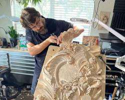 Alexander Grabovetskiy carving a piece of wood in a workshop.