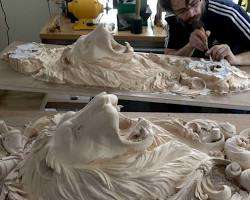 A person is focused on carving detailed lion sculptures on a workbench, showcasing skill and creativity in wood carving. Perfect for those interested in taking wood carving classes or lessons to enhance their craft!