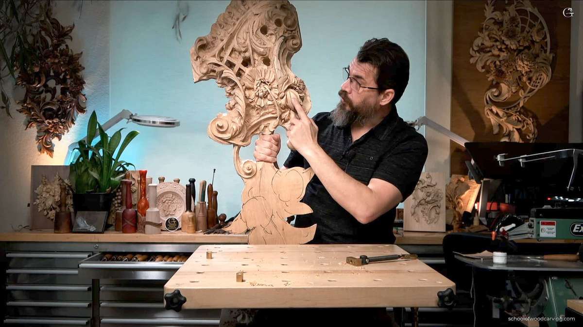 A man with a beard is carving a piece of wood.