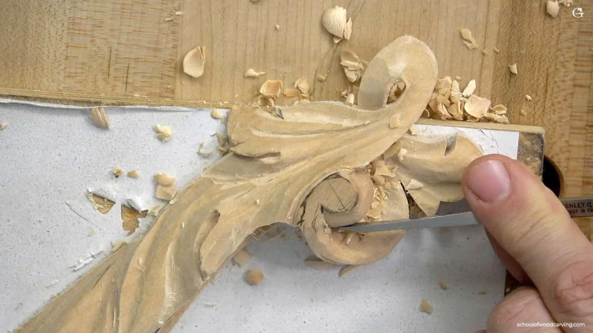 A gouge slicing an acanthus lobe exactly where it rolls over the edge of the molding profile