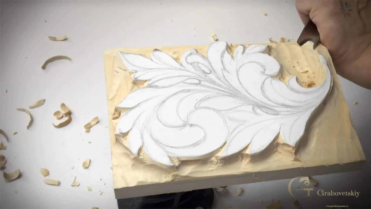 Carved leaf standing clear of a lowered ground with an even pale surface and chips scattered all around it
