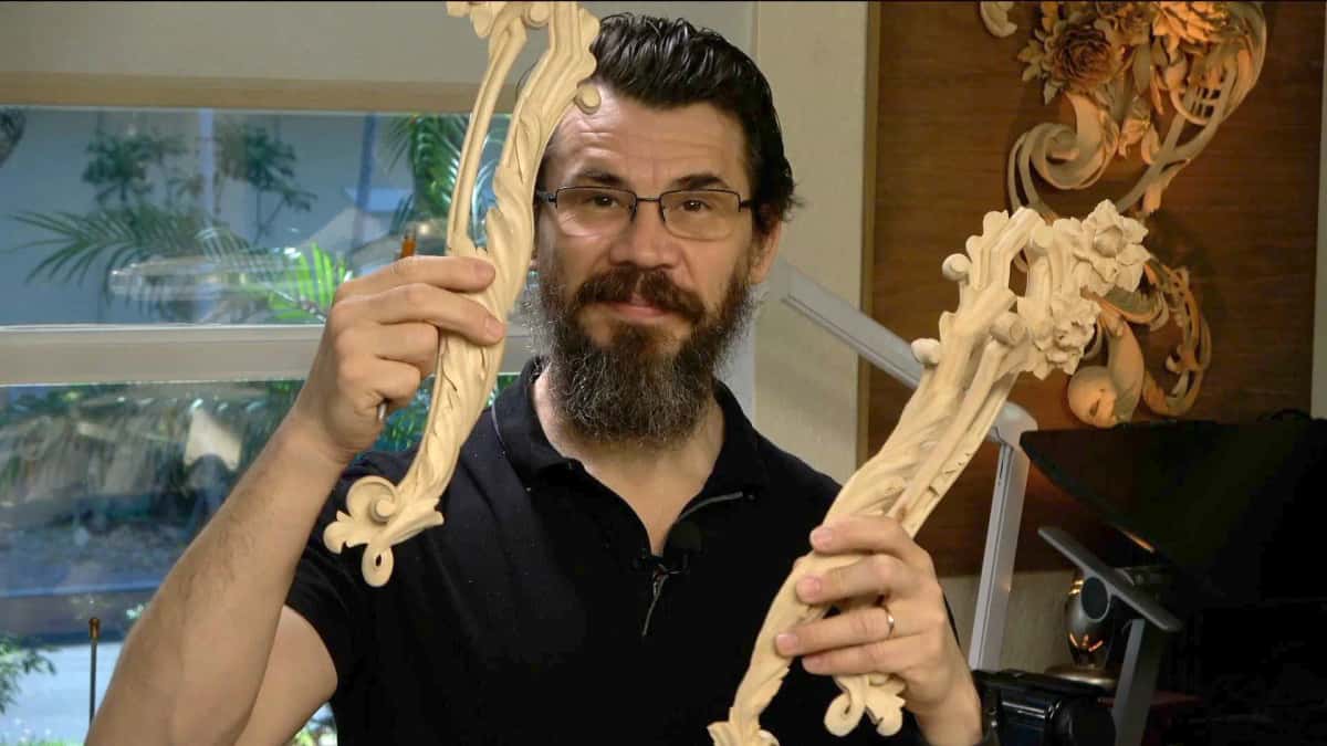 Alexander Grabovetskiy holding the completed carved molding up in both hands in his shop