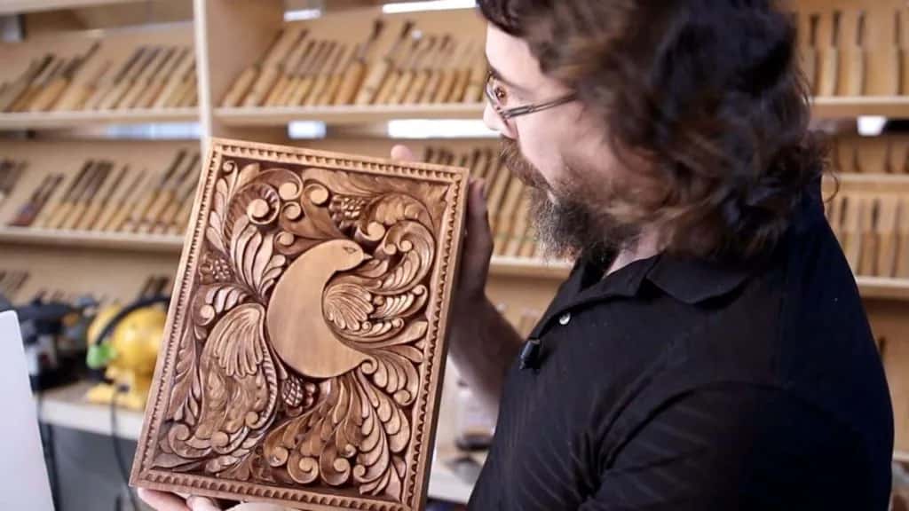 Alexander holding the finished curly board in front of the tool wall