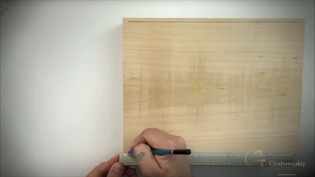 Drawing the first border line along a steel rule laid across the face of the board