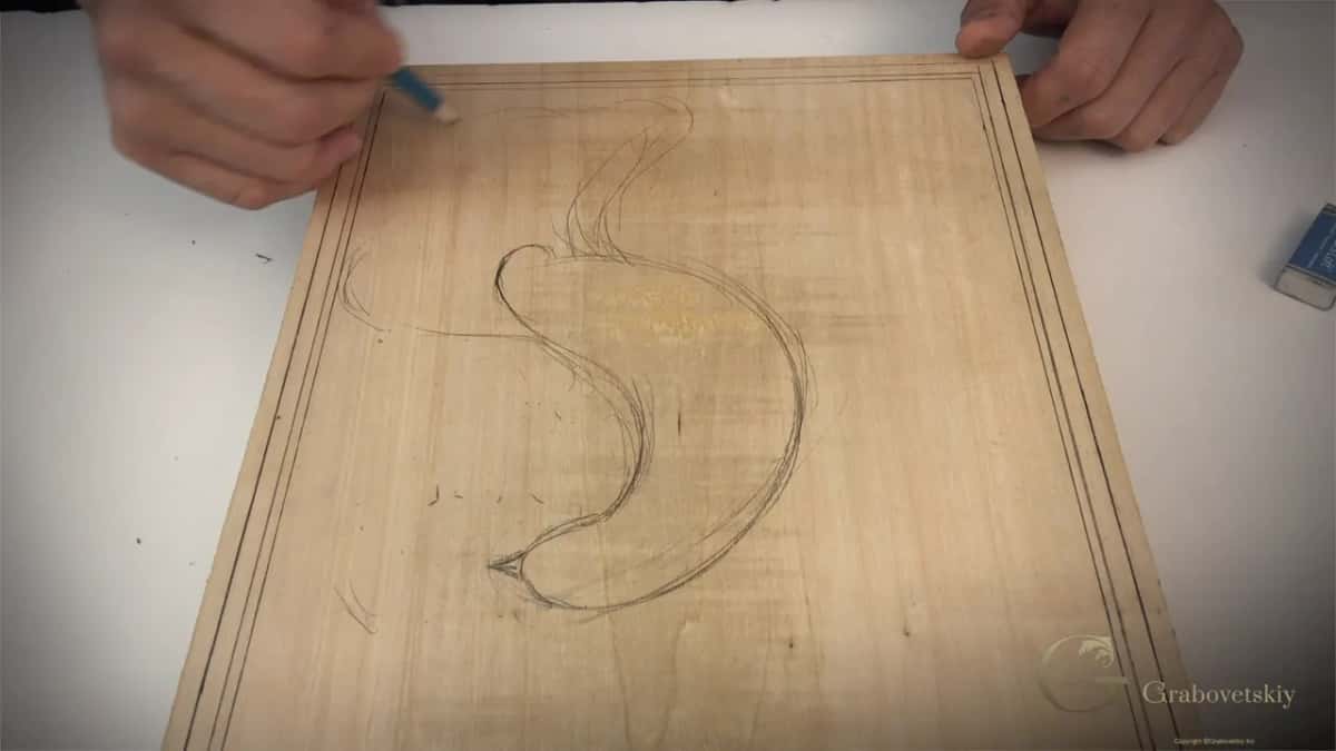 Body and tail of the stylized bird sketched onto the board, eraser still in hand