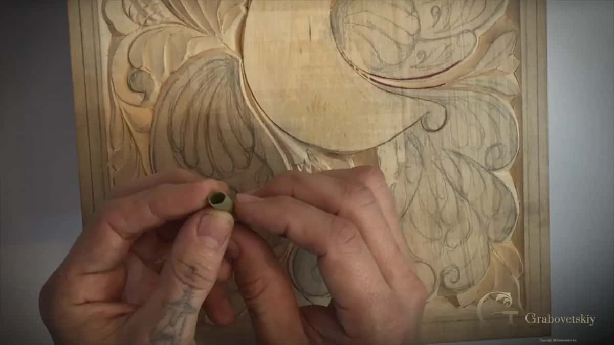 A hollow stalk of Dutch reed held over the half carved board, the abrasive plant used before sandpaper