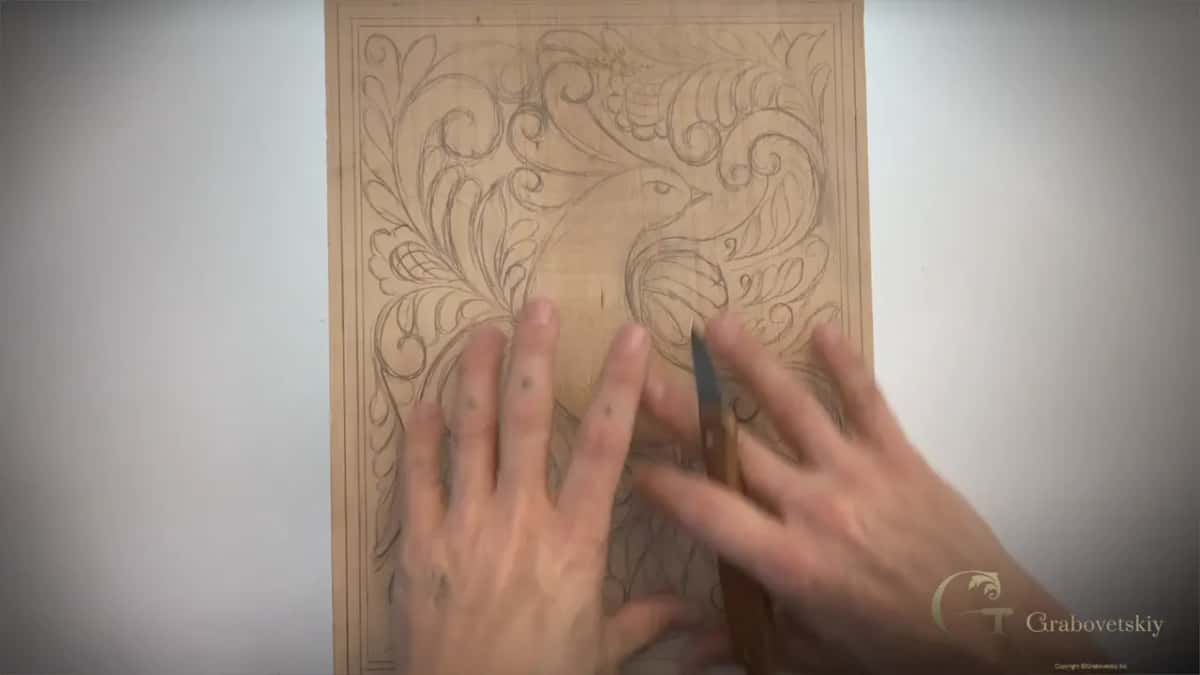 Chip carving knife held up beside the drawn board at the start of the carving