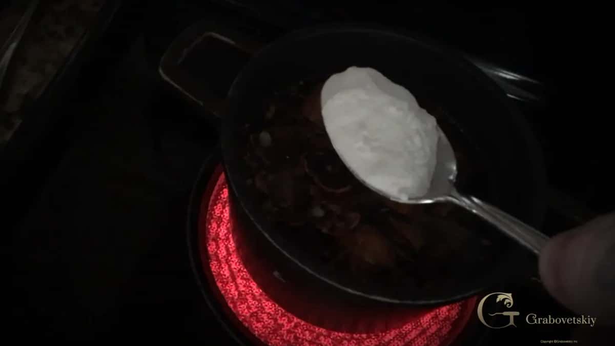 Spoonful of baking soda going into the pan where the shells boil down into a dark stain