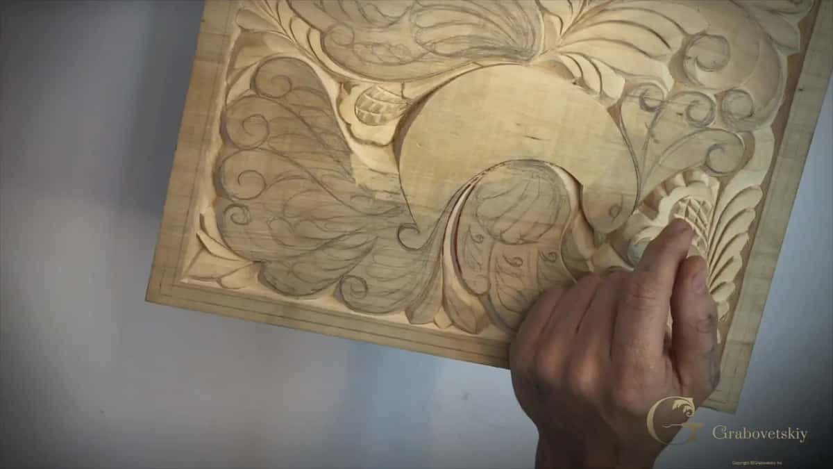 Board half carved, the curls dropped into relief while pencil lines still show on the rest