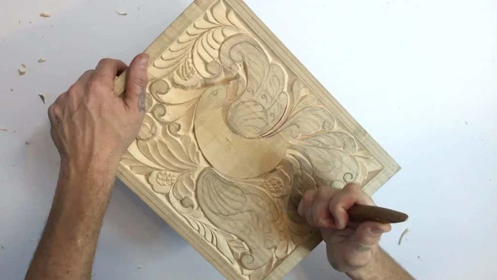 Both hands on the bird board, one steadying while the knife rolls a curl over