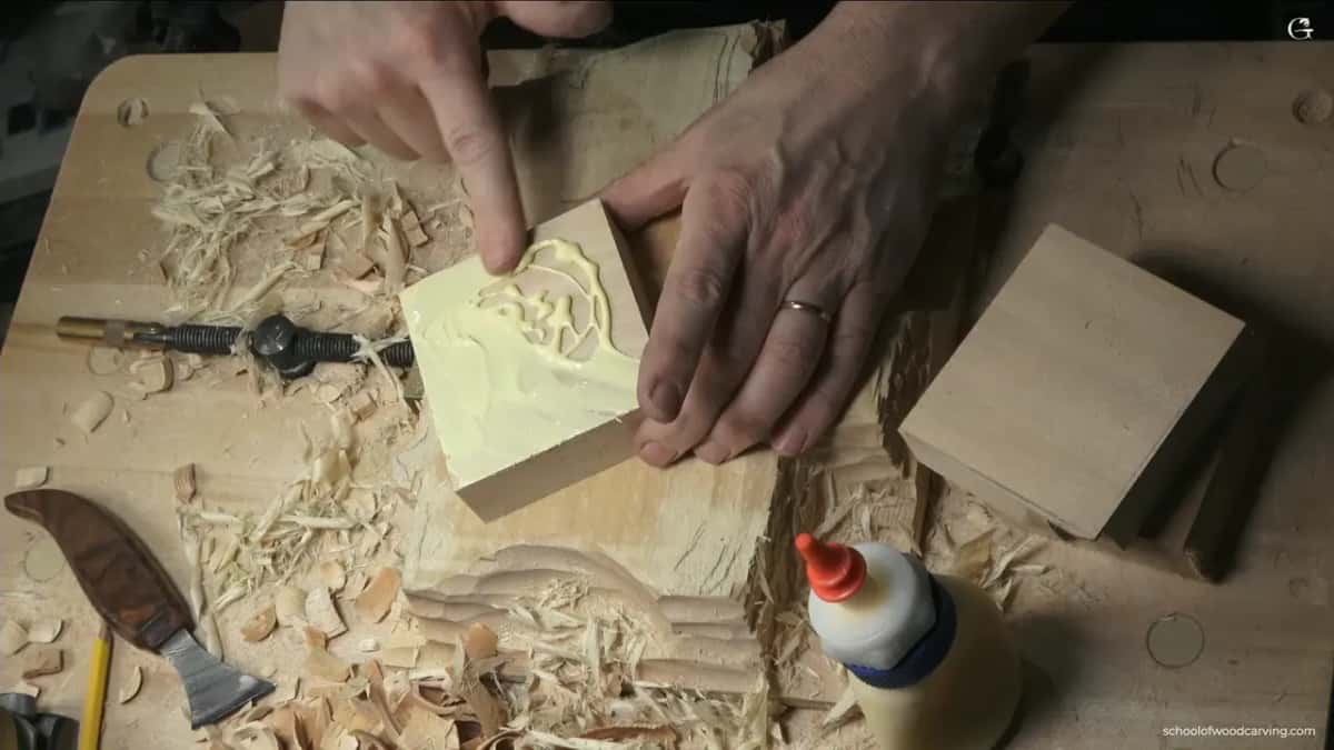 Spreading glue with a finger and wiggling the block until it sucks down onto the panel