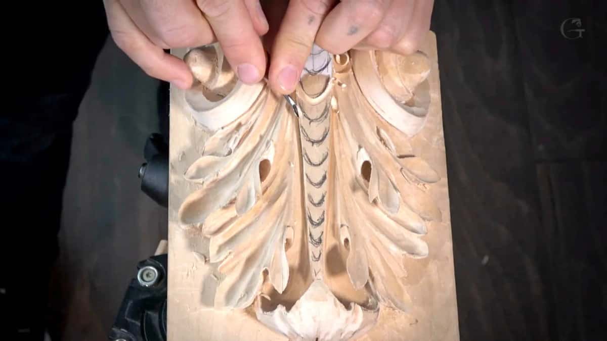 Opening the deep eyes Both hands at the top of a Roman leaf, the near one steadying while the far one drives a small gouge