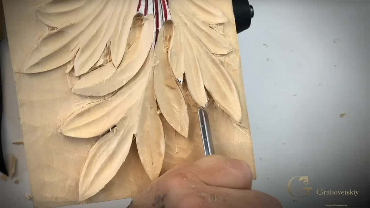 Chrome gouge shaft laid into a deep acanthus lobe, with a striped paper pattern pinned above the panel