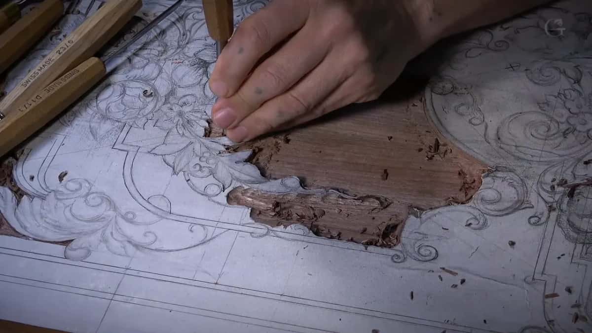 Gouge in hand, the ground taken out around a drawn shield while the rest of the design stays on paper