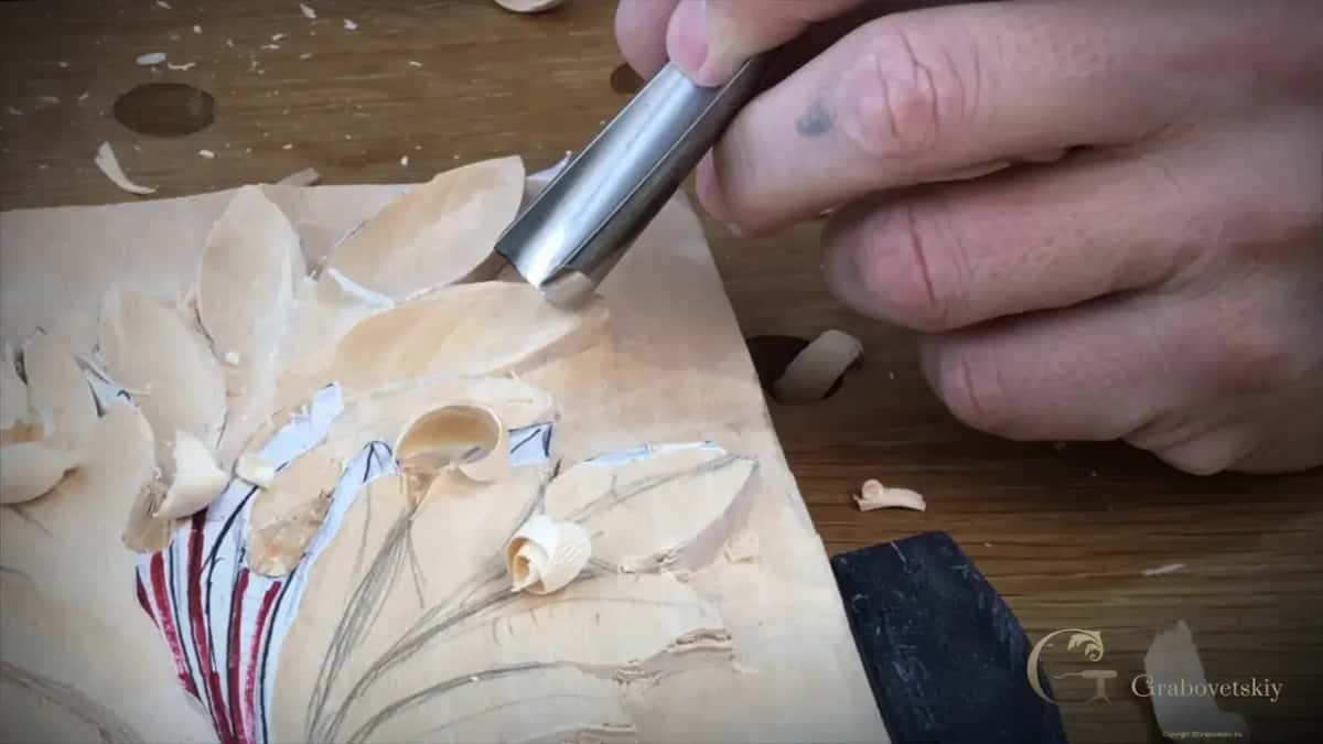 Layout lines in red and blue still drawn on a carved leaf as the edge slices through it