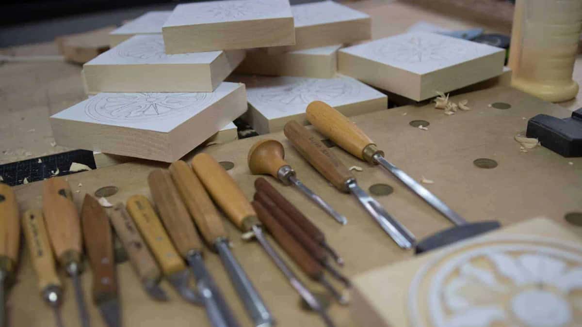 Gouges and knives laid out in a row beside patterned blanks
