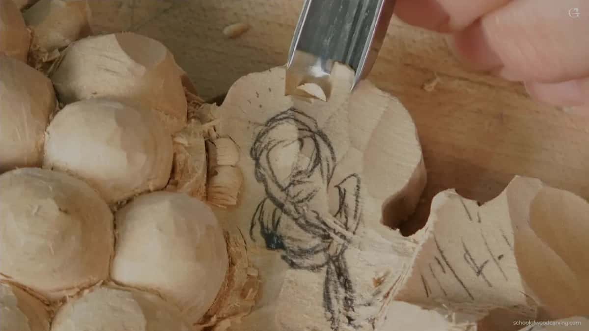 A gouge slices a pencilled leaf beside carved grapes.