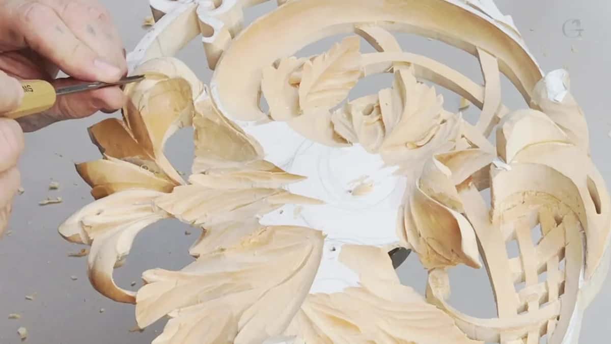 A knife reaches into a pierced flower panel in which every leaf and curl runs a different way from its neighbour.