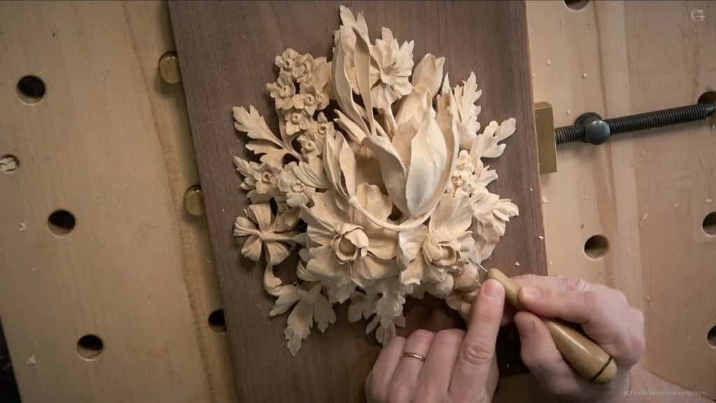 Foliage clamped to a bench, a gouge working into the leaves