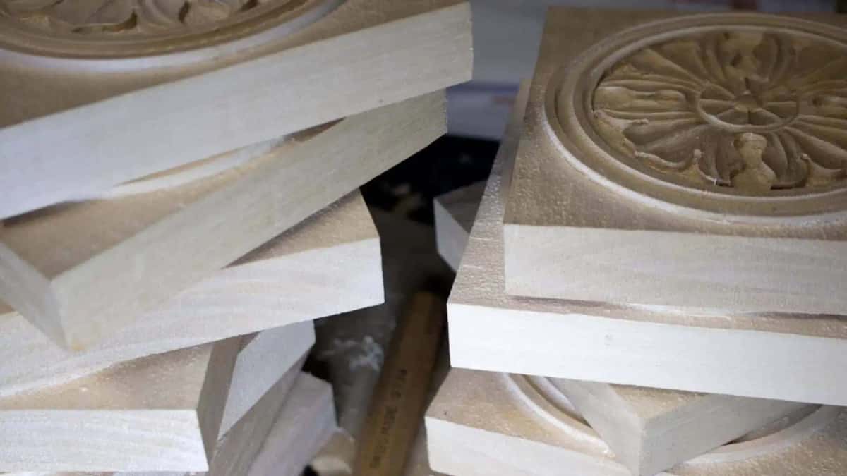 Growth rings visible on the sawn ends of a stack of pale blanks, one finished carving behind