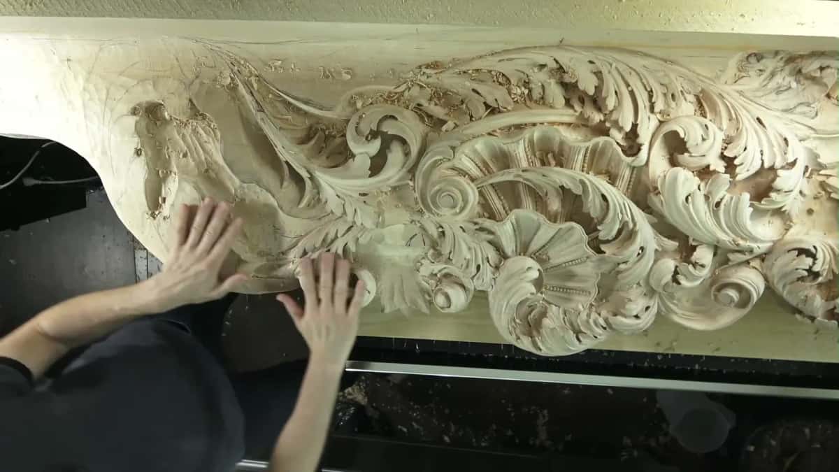 Forty years, no crack Two hands resting flat on a long carved basswood frieze that never split