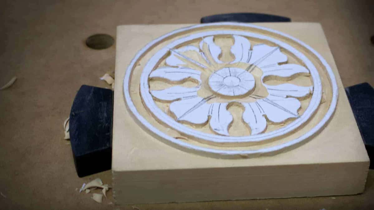 Lowering the background around a partly carved rosette held by bench clamps