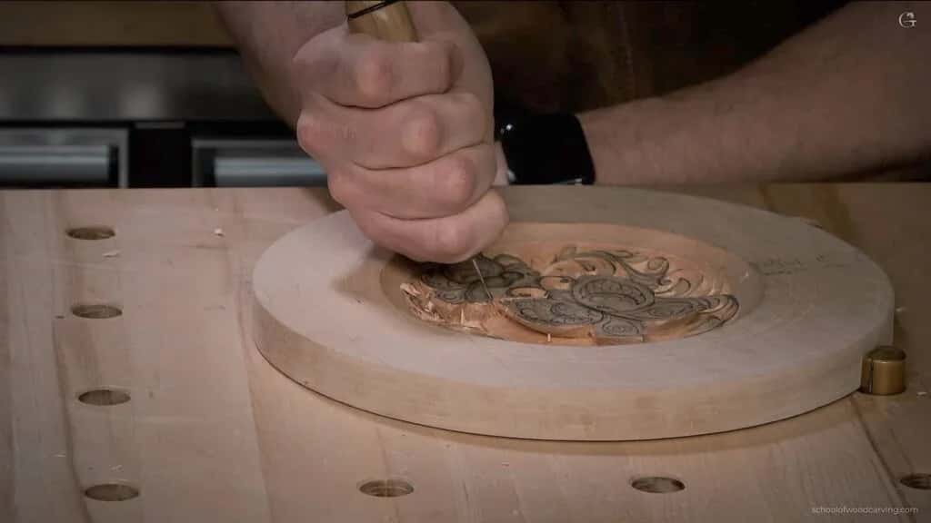 A gouge cutting into the carved centre of the round plate