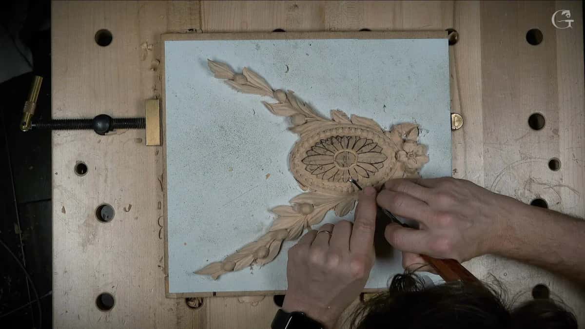 Carved oval rosette with laurel rising off a painted board while a pencil redraws part of it