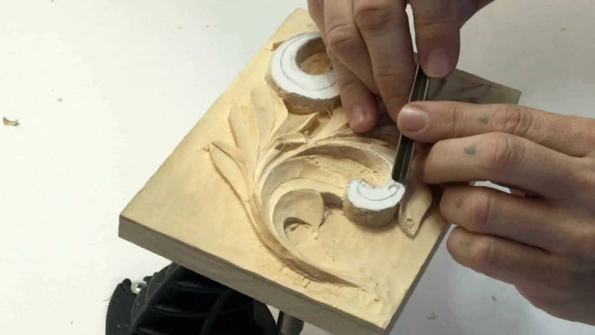 A flat chisel paring wood beside a carved acanthus eye, in very small bites