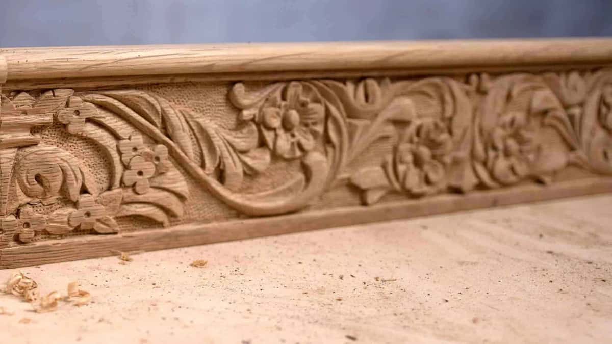 Raking light thrown across the stippled ground behind a newly carved acanthus scroll and its flowers