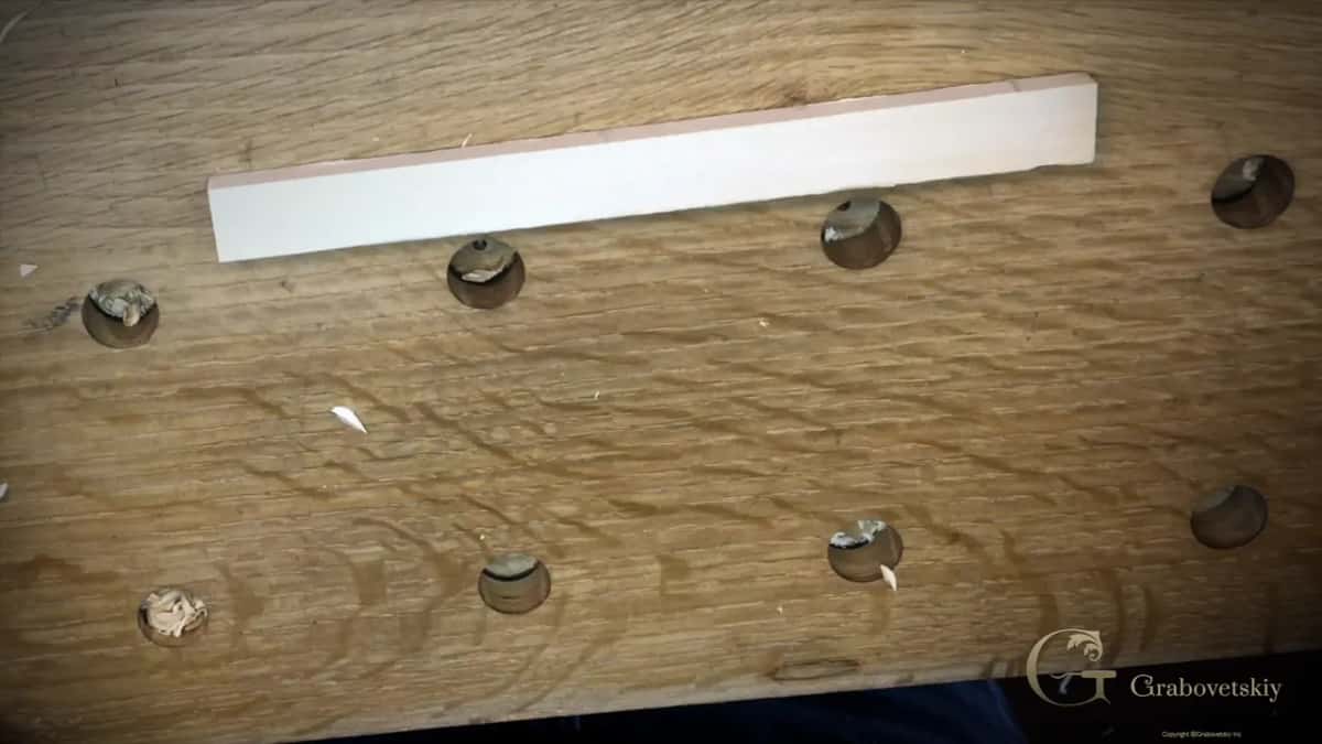A thin pale plank alone on a wide oak bench.