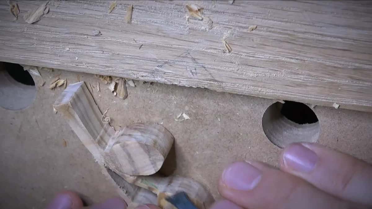 A sawn board face left hairy and torn, with three streaked carved leaves lying below it.